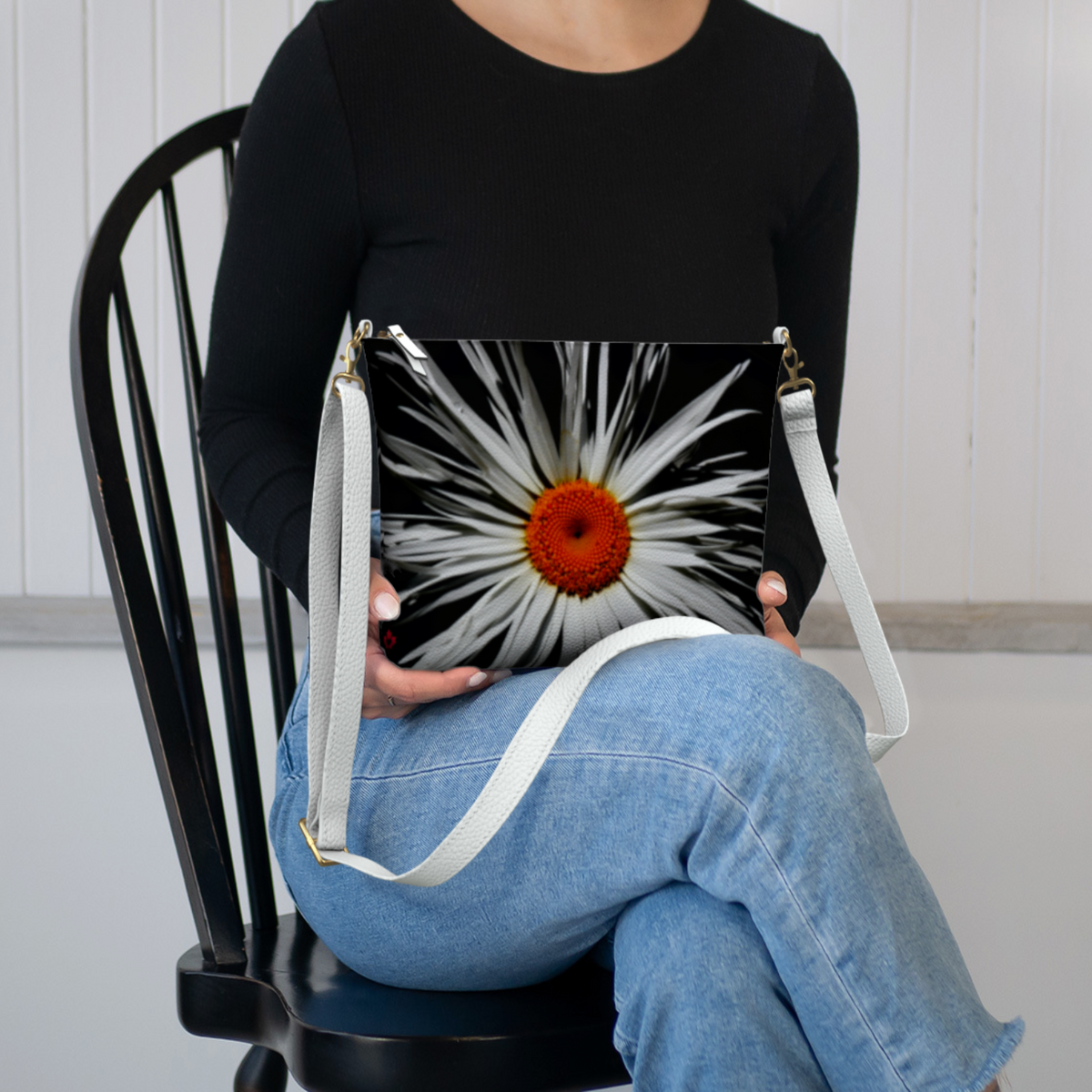 Person holding a bag with a floral design, sitting on a chair.