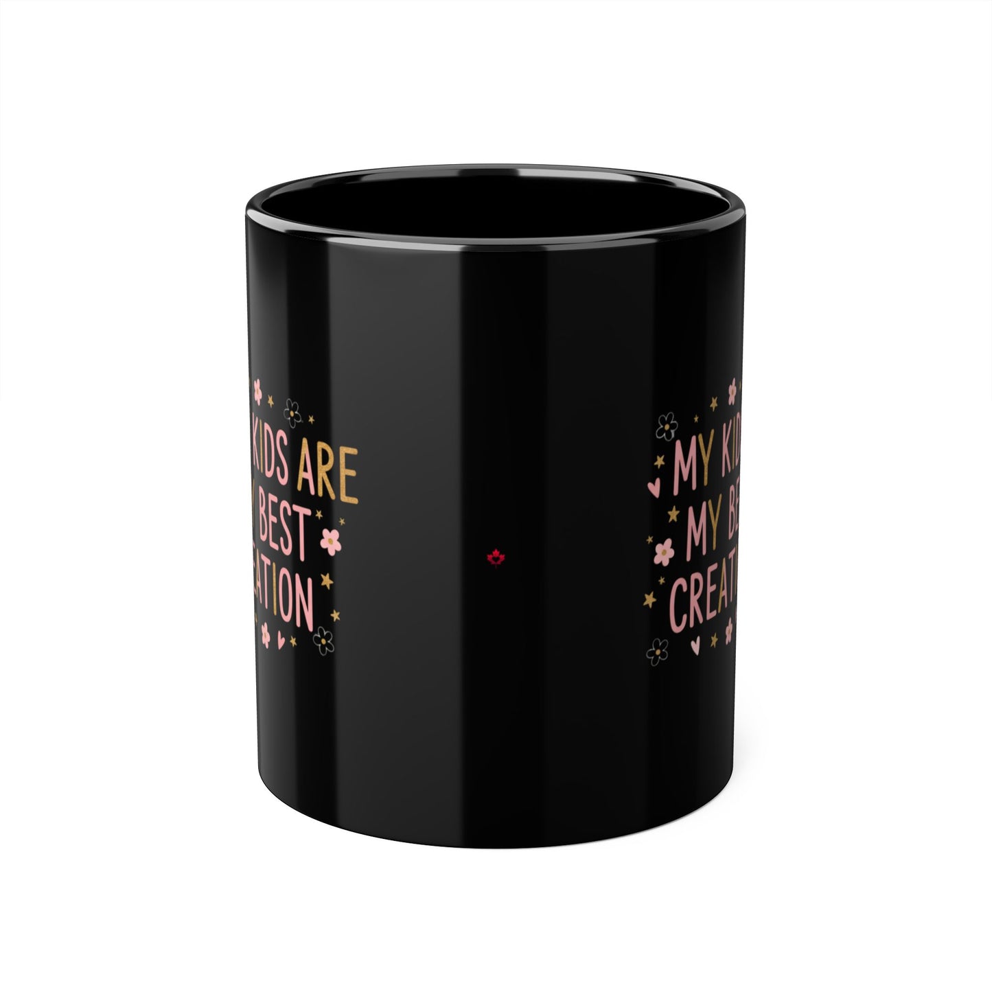 A glossy black ceramic mug with gold and pink text reading 'Kids are my greatest creation'  decorated with small pink flowers and gold stars, shown on a plain white background.

