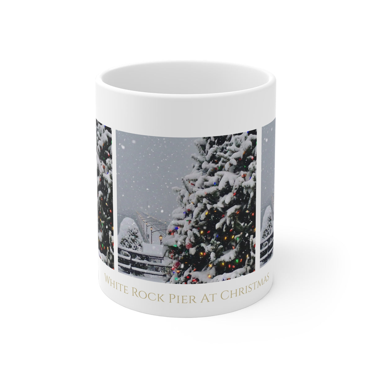 A white ceramic mug featuring a printed triptych of snowy Christmas trees with colorful lights and the text 'WHITE ROCK PIER AT CHRISTMAS' in gold at the bottom, shown on a clean white background.