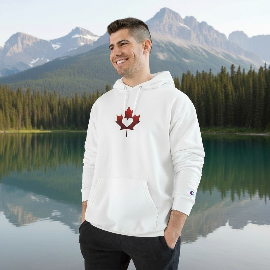 Man wearing a white hoodie with a red maple leaf design in front of a mountain lake
