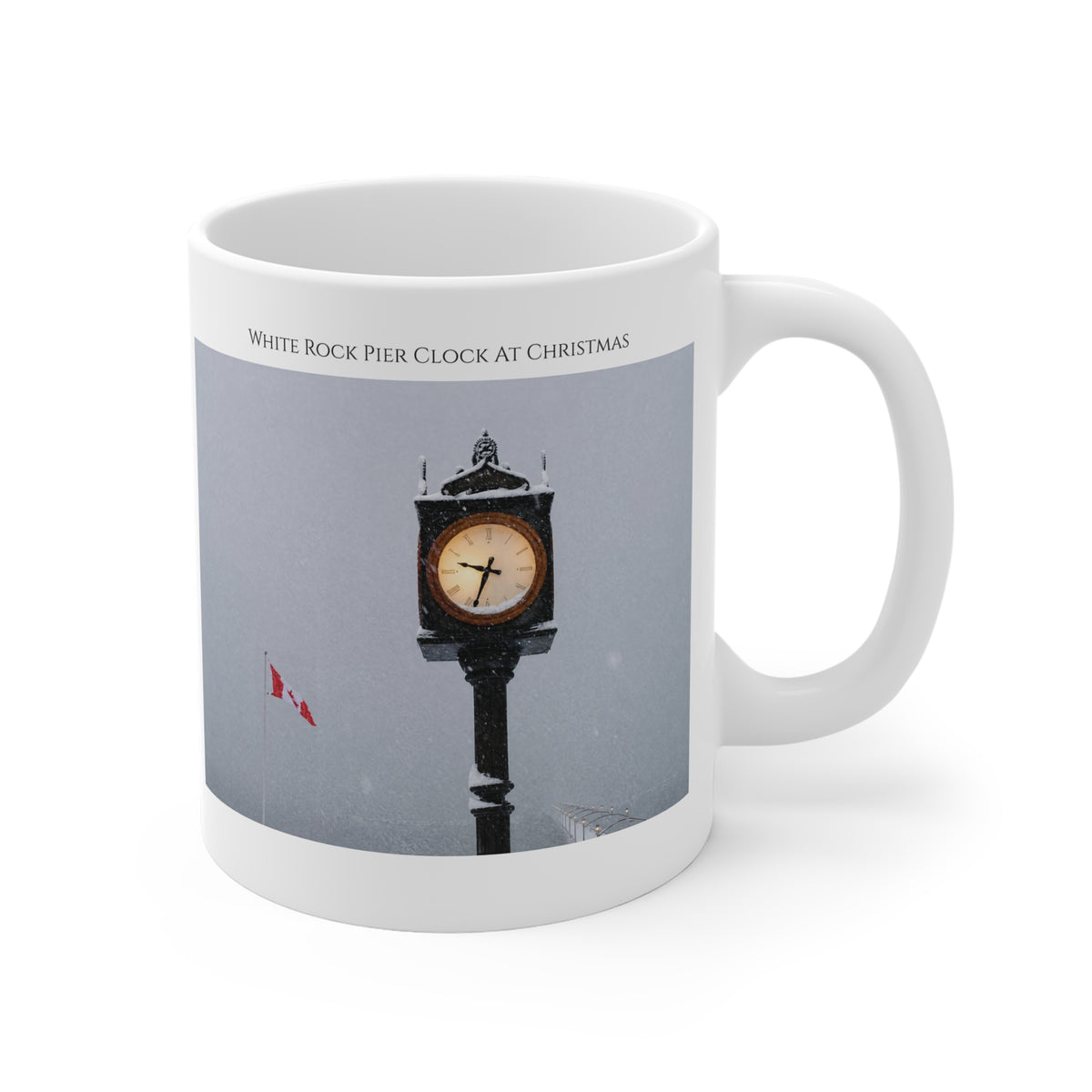 A white ceramic mug featuring a printed photograph of a snow-covered clock on White Rock Pier in Vancouver during Christmas, with the text 'WHITE ROCK PIER CLOCK AT CHRISTMAS' printed above the image.