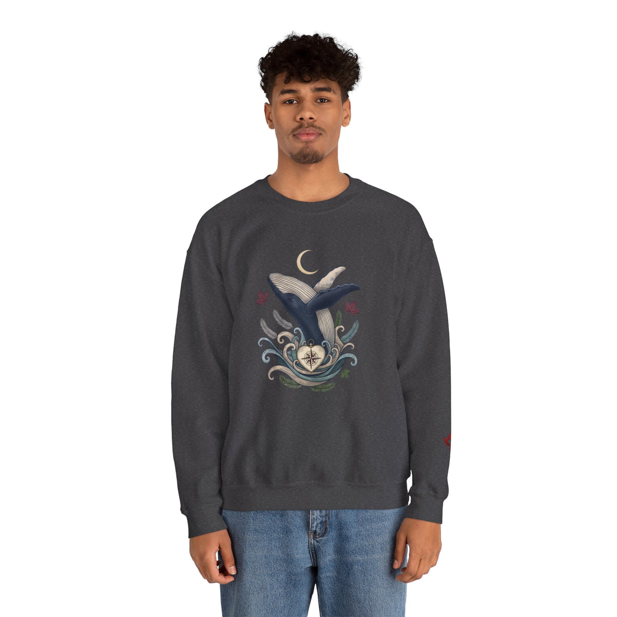 Make Love Your Compass Whale Moon Sweatshirt: A male model wearing a grey crewneck featuring a graphic print of a blue and white whale with a crescent moon and swirling waves against a white background.
