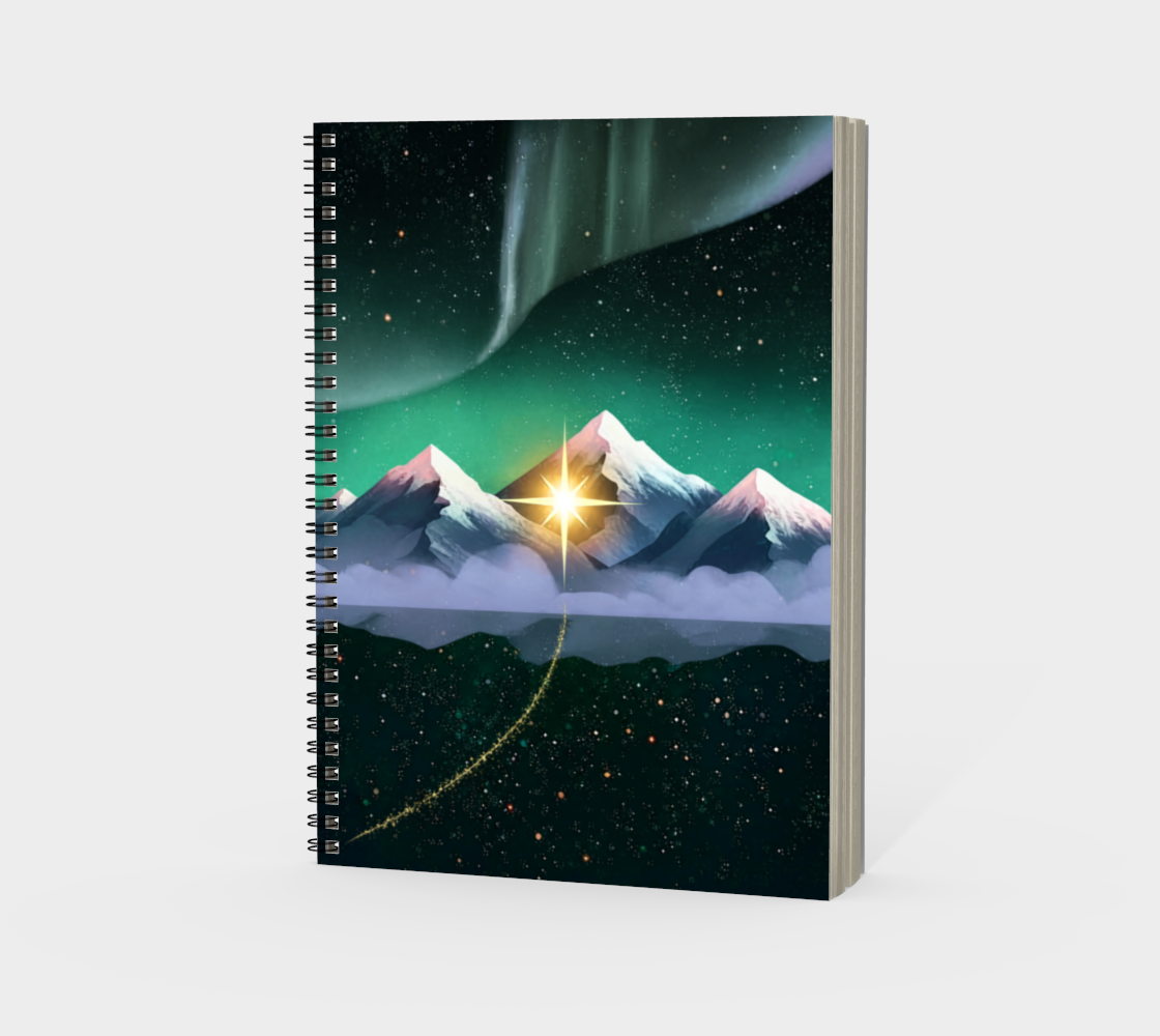 A spiral-bound notebook standing upright on a light grey background. The notebook cover features a stylized illustration of snow-capped mountains under a starry night sky with green aurora lights and a glowing sunburst.