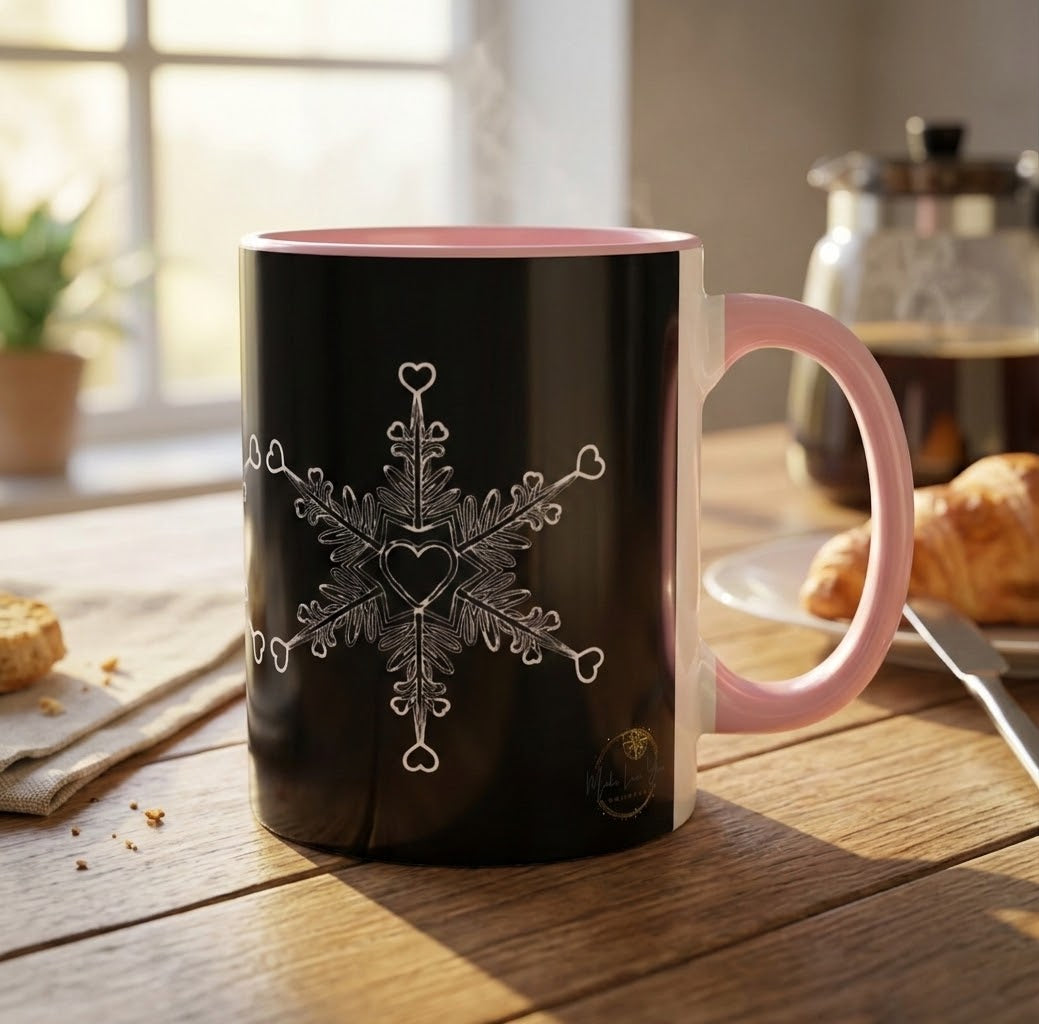 Make Love Your Compass 11oz ceramic accent mug with a black exterior and vibrant pink interior and handle, featuring a white snowflake design made of tiny hearts on a wooden table. 